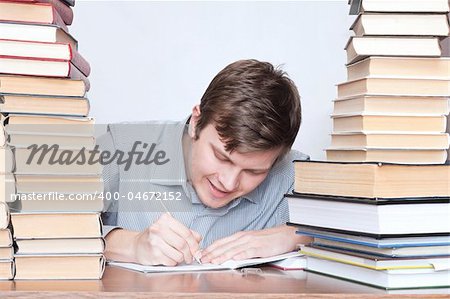 Young student write in notebook between books