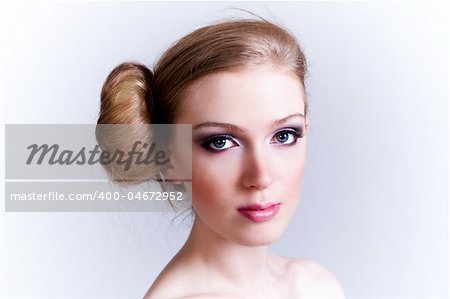 Attractive young woman with her hair in a bun looks towards the camera. Horizontal shot.