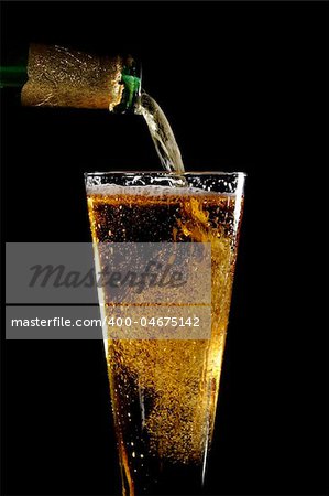 A glass of beer being poured with a black background