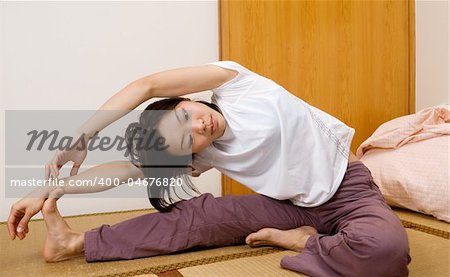 Asian woman excise on ground of room in home.