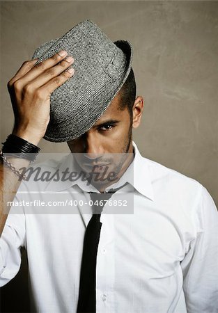 Male model stares at camera with hand on hat