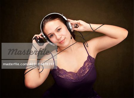 Pretty girl in funky purple outfit on green background with personal audio device