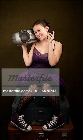 Pretty girl in funky purple outfit on green background with big radio