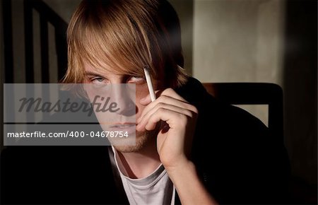 Depressed young man smoking in a tenement hovel