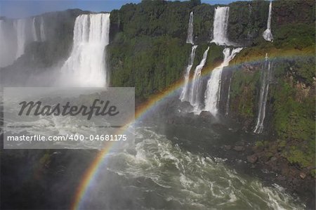 Iguassu waterfalls with rainbow on a sunny day early in the morning. The biggest waterfalls on earth.