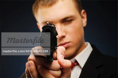 Young man with pistol over dark background