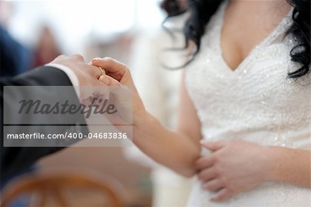 Bride is putting the ring on groom's finger