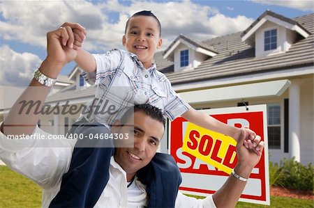 Excited Hispanic Father and Son with Sold For Sale Real Estate Sign in Front of House.