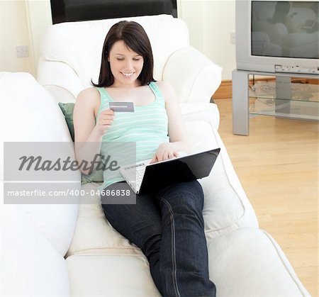 Charming woman shopping on-line lying on a sofa at home