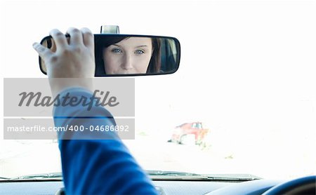 Caucasian woman sitting on driver's seat and looking in the rear-view mirror