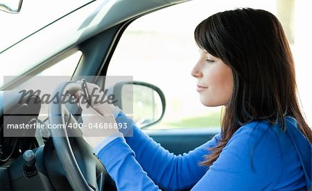 Attractive brunette teen girl using a mobile phone while driving