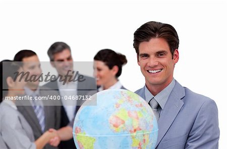 Happy businessman holding a globe in front of his team against a white background