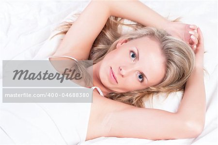 Young pretty girl lying in bed. Genuine smile