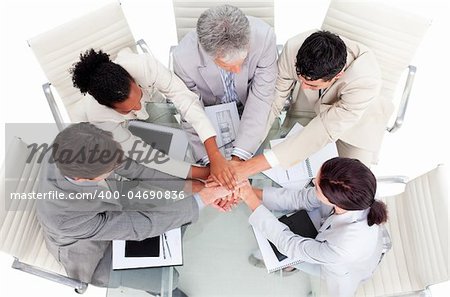 Cheerful international business people with hands together in a meeting