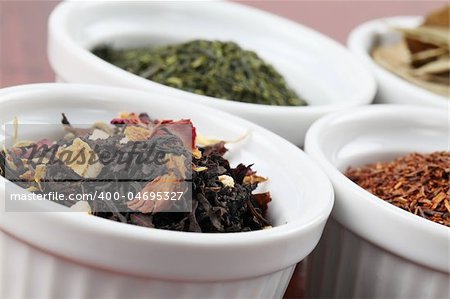 White bowls with various kinds of tea - focus on black tea with flower petals and dried orange peel