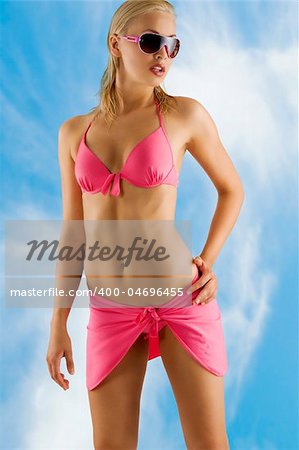 stunning sensual blond woman with wet hair in pink bikini with sunglasses taking pose