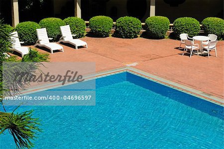 swimming pool and chaise longues in a yard