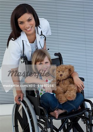 Smiling Little girl on a wheelchair holding her teddy bear