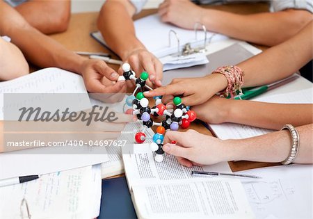 Close-up of teenagers studying and holding molecules in a library
