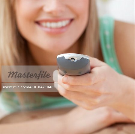 Close-up of a blond woman watching TV lying on the floor at home