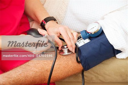 Nurse taking a patient's blood pressure using a sphygmomanometer.  Closeup view.