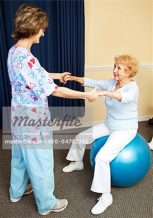 Physical therapist using pilates ball to work with senior chiropractic patient.