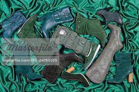 Female shoes and boots placed on green satin. Studio shot