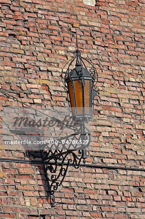 Close-up of old style street lamp on a brick castle wall