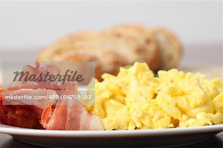 Close-up of scrambled eggs and slices of bacon on a plate