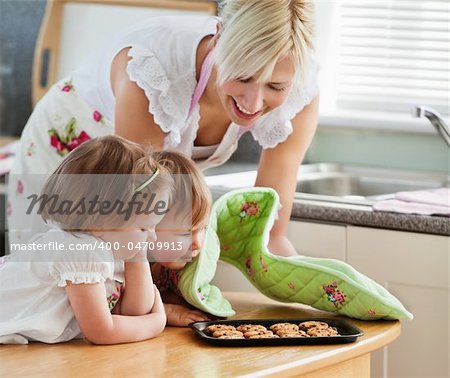 Smiling woman baking cookies with her daughters in kitchen