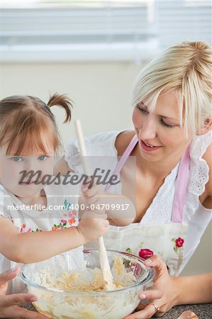 Simper woman baking cookies with her daughter in kitchen