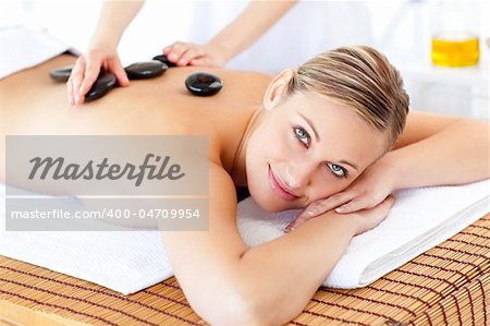 Smiling caucasian woman receiving a massage with hot stone in a spa center