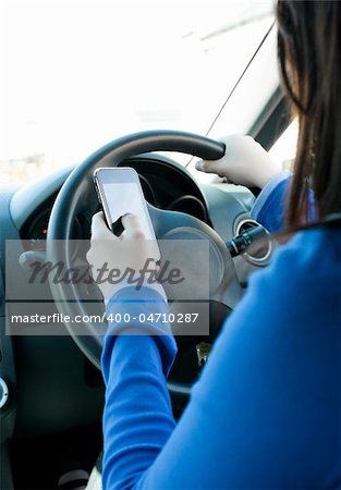 Young brunette woman using her cellphone while driving in her car