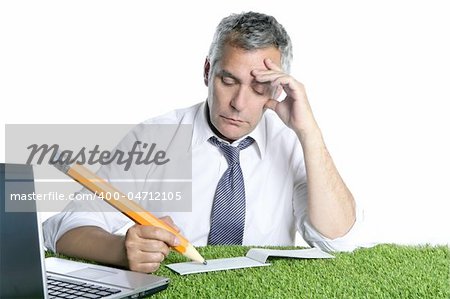 businessman senior sign bank check pensively humor gesture big pencil green grass desk