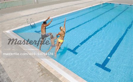 happy young family have fun on swimming pool  at summer vacation running and jumping in the pool