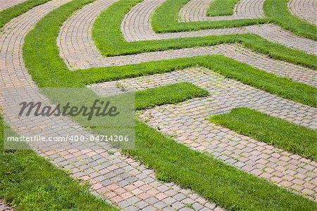 Park maze with a cobblestone walkway and grass boundaries. Horizontal shot.