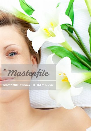 Beautiful woman lying on a massage table in a spa with flowers