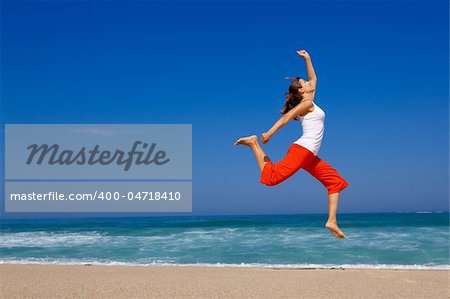 Beautiful young woman jumping on  the beach