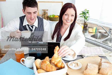 Couple of businesspeople using a laptop during their breakfast at home