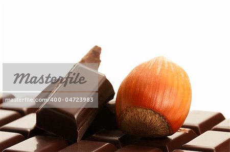 hazelnut and plain chocolate pieces on a plain chocolate bar on white background