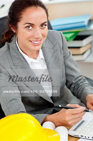 Smiling female architect holding a pen in her office at her desk