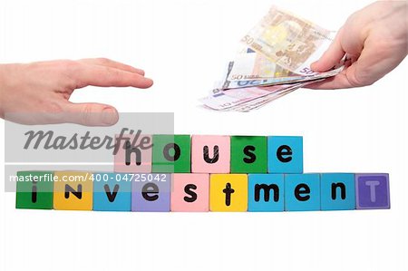 toy letters that spell house investment with cash in hands against a white background with clipping path