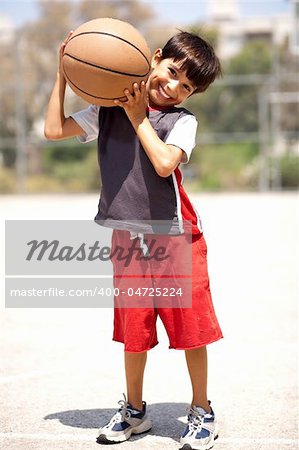 Boy with basketball on his shoulders, outdoors