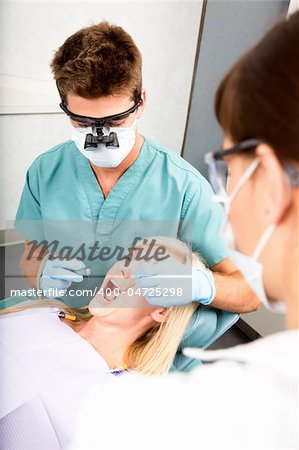 A dentist with assistant working on a patient