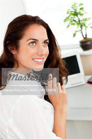 Attractive businesswoman holding glasses and sitting at her desk in her office