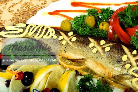Stuffed baked fish served with lemon and salad