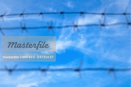 Barbed Wire photographed against a background of blue cloudy sky. Focus on the sky