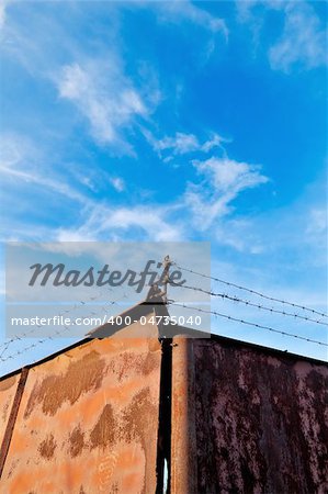 Barbed wire fence photographed against a background of blue cloudy sky.