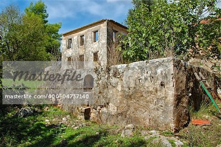 Vintage stone tank for grape stomping and derelict house ruins. Zakynthos, Greece.