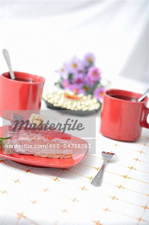 Fruit dessert with tea, violet flowers and napkin in red concept
